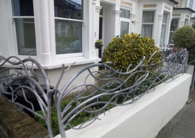 Decorative metal railing with a vine-like design in front of a residential property.