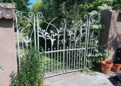 Decorative wrought iron gate with floral patterns, leading into a garden area.